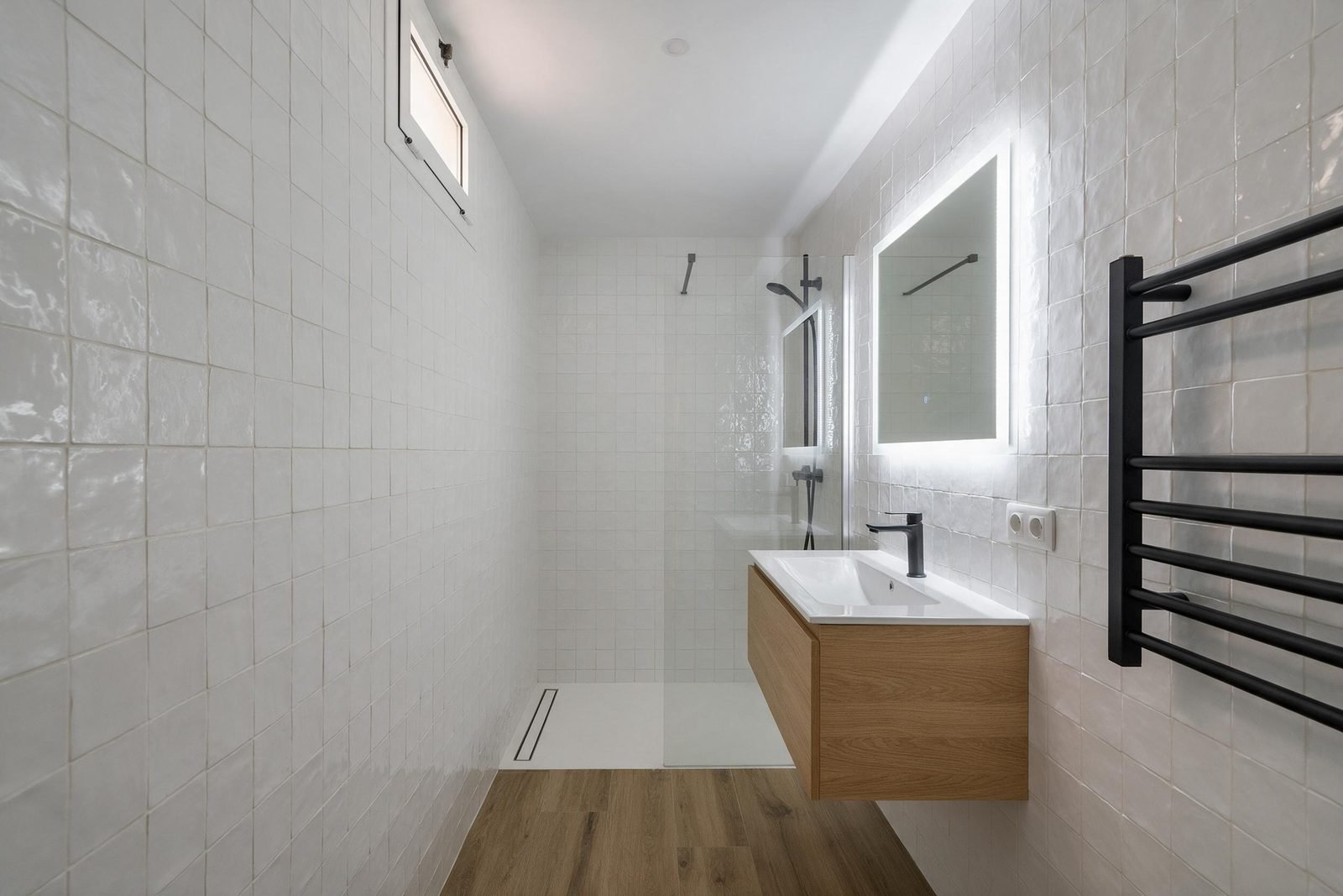 Baño estrecho reformado en Madrid con azulejo zellige blanco y ducha con desagüe lineal