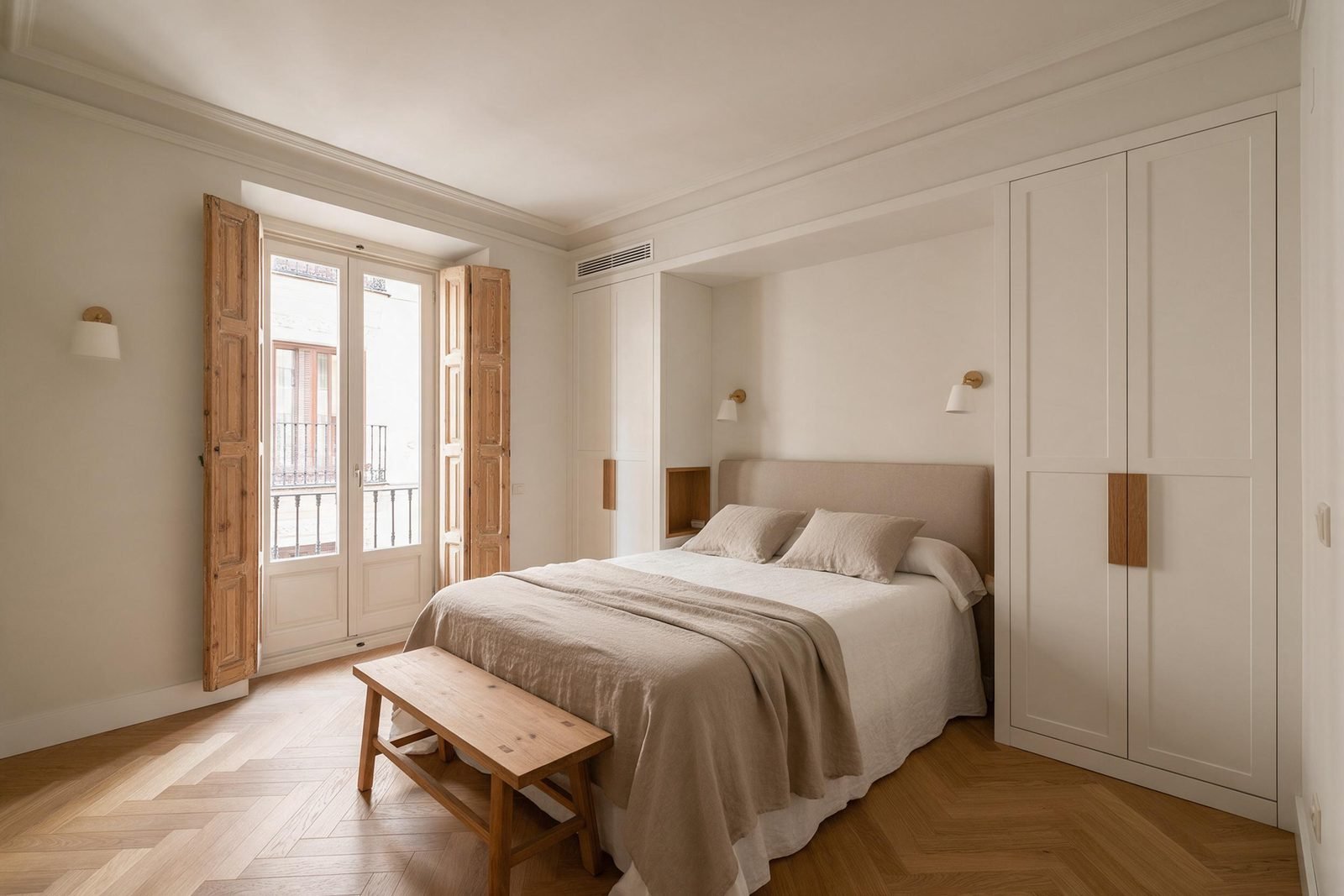 Dormitorio principal tras una reforma integral en Madrid, con armarios empotrados y balcón con contraventanas restauradas